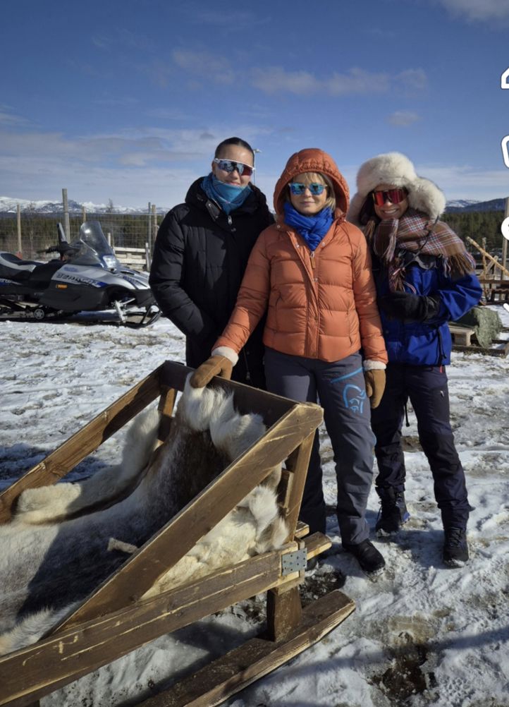 En gruppe mennesker som står ved siden av en treslede i snøen